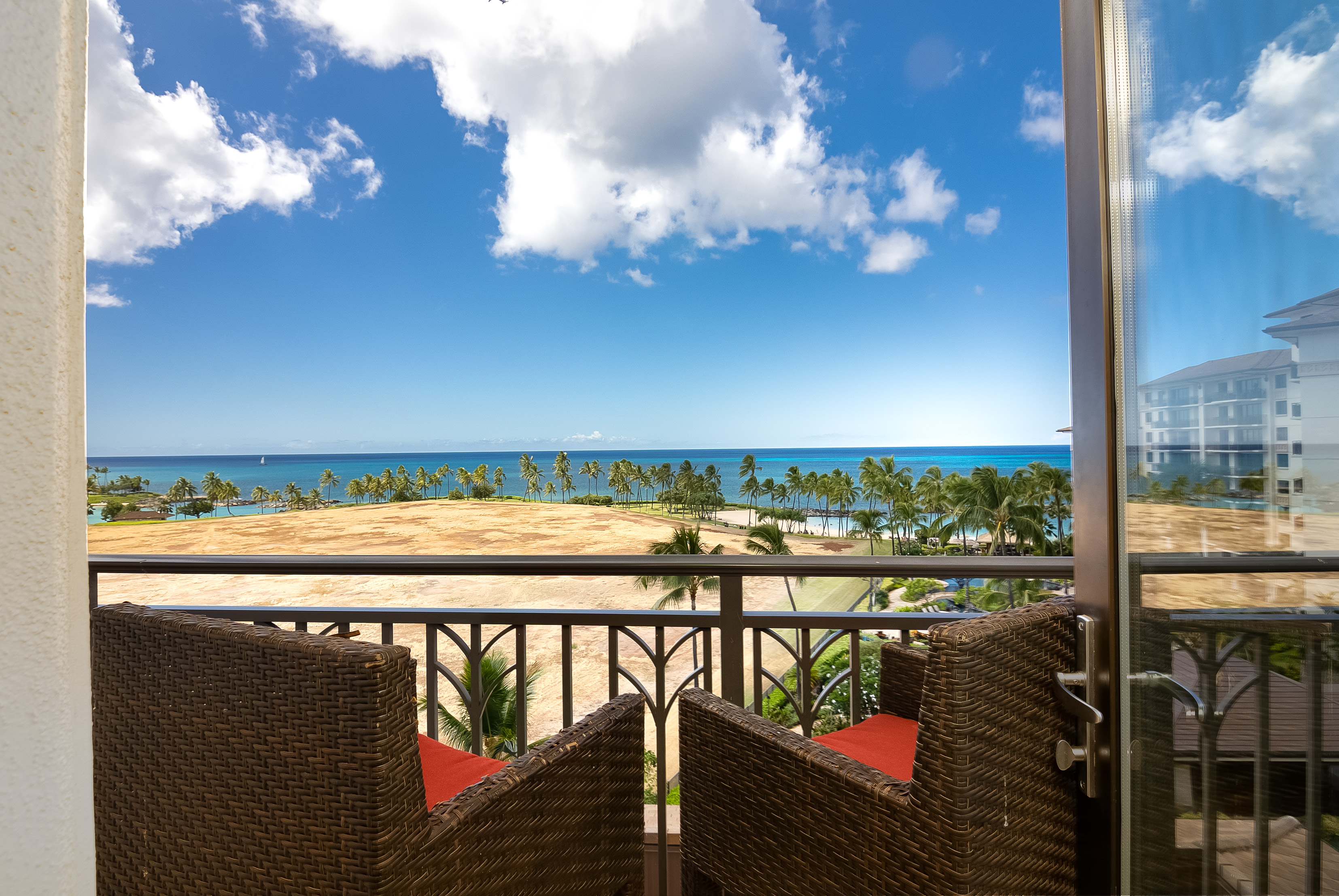 Ocean and shoreline view framed by two chairs on the condo lanai